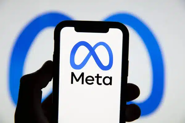 A person is holding a phone with the meta logo on it.